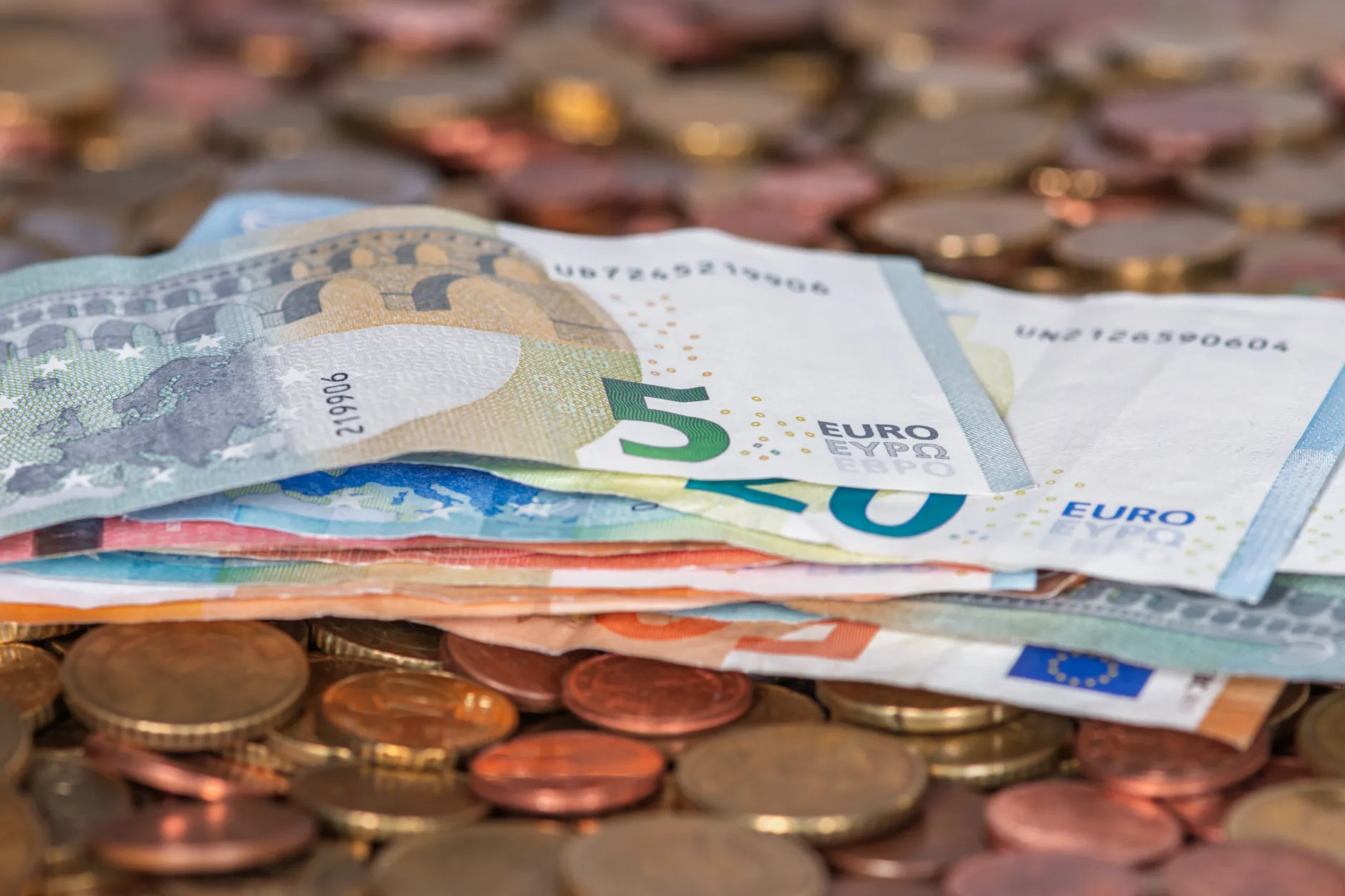 Gestapelte Euro-Geldscheine und Münzen auf einem Tisch