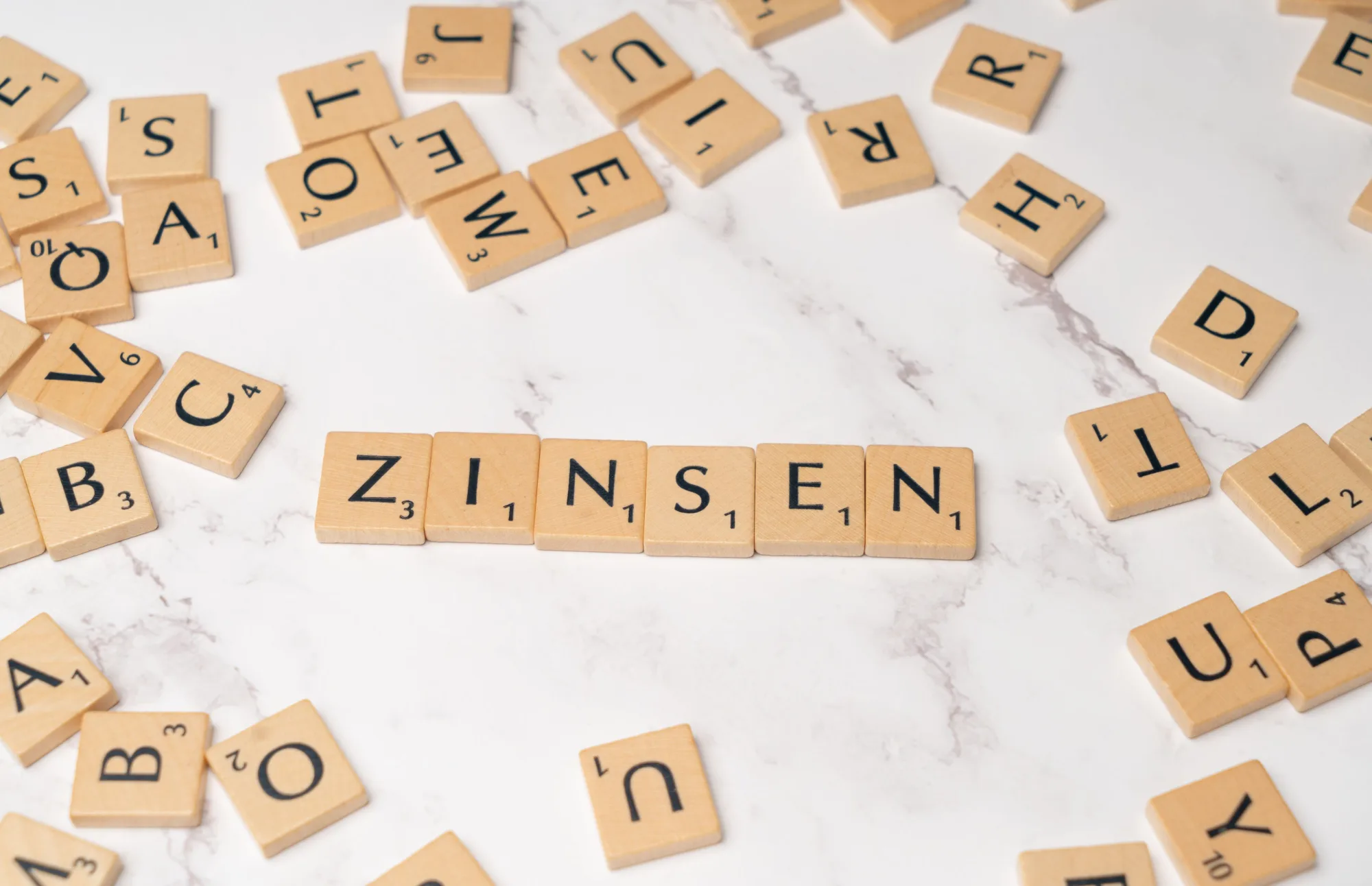 Holzbuchstaben bilden das Wort Zinsen auf einer hellen Fläche