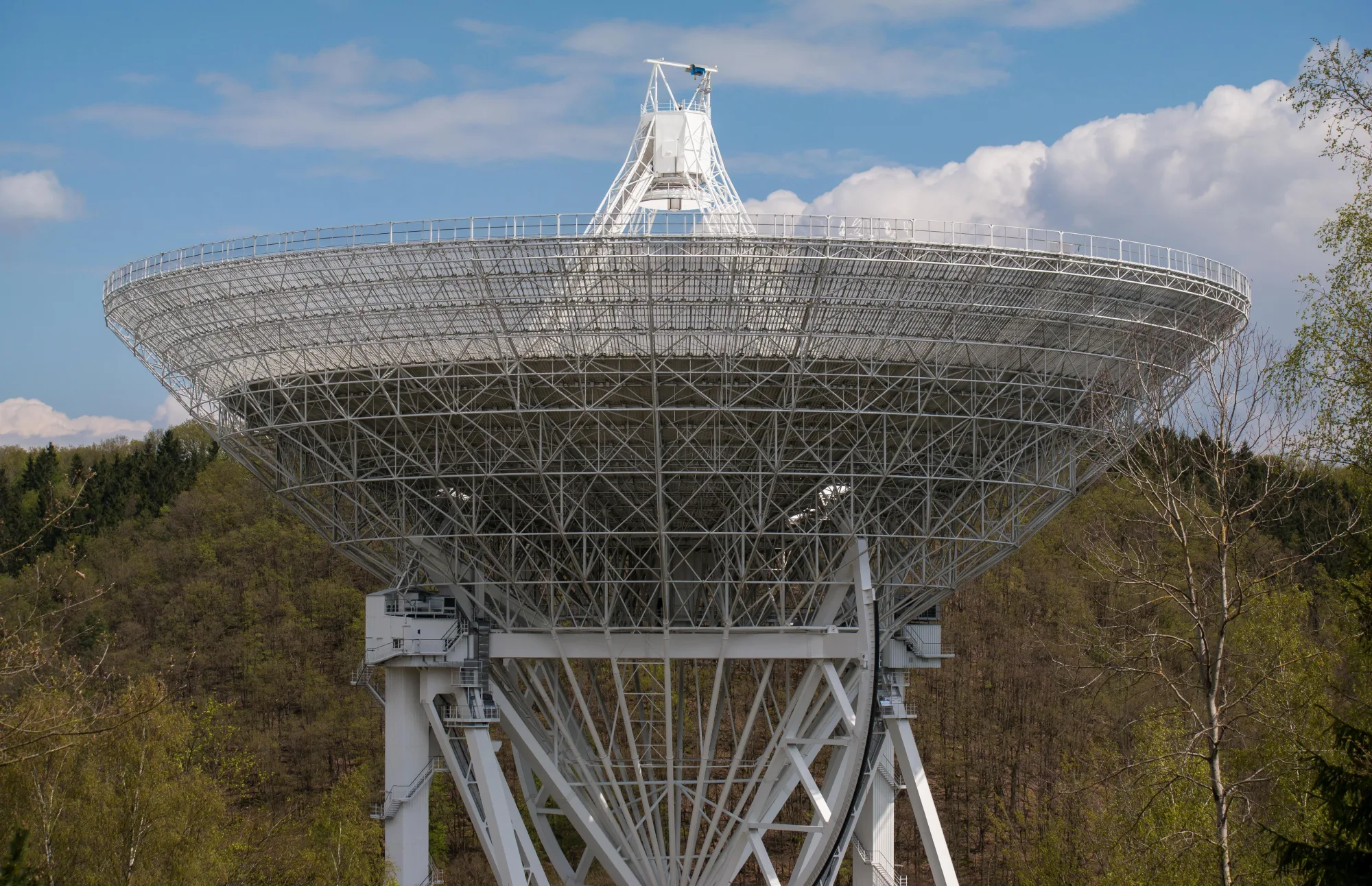Ein großes Radioteleskop richtet sich unter freiem Himmel zum Himmel.