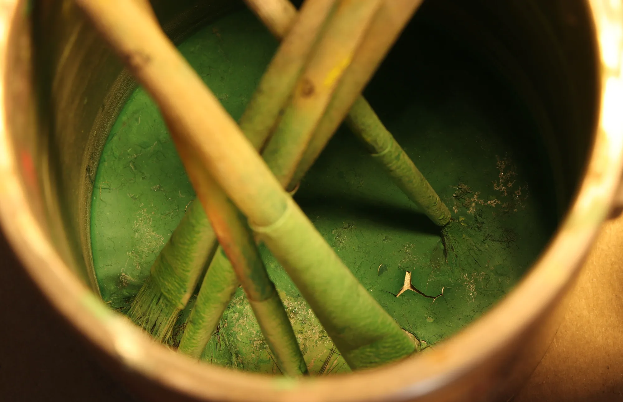 Pinsel stehen in einem Eimer mit grüner Farbe