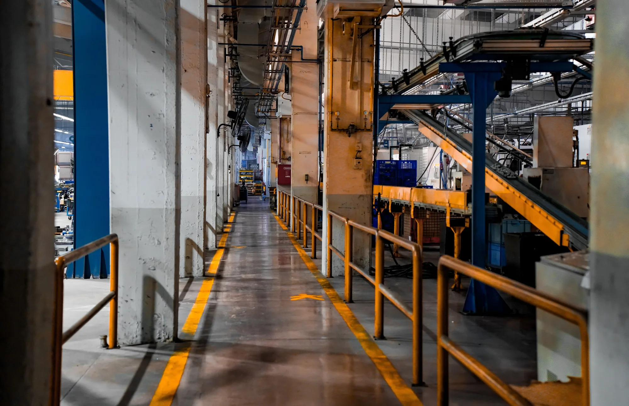 Förderbänder und Maschinen stehen in einer Industriehalle.