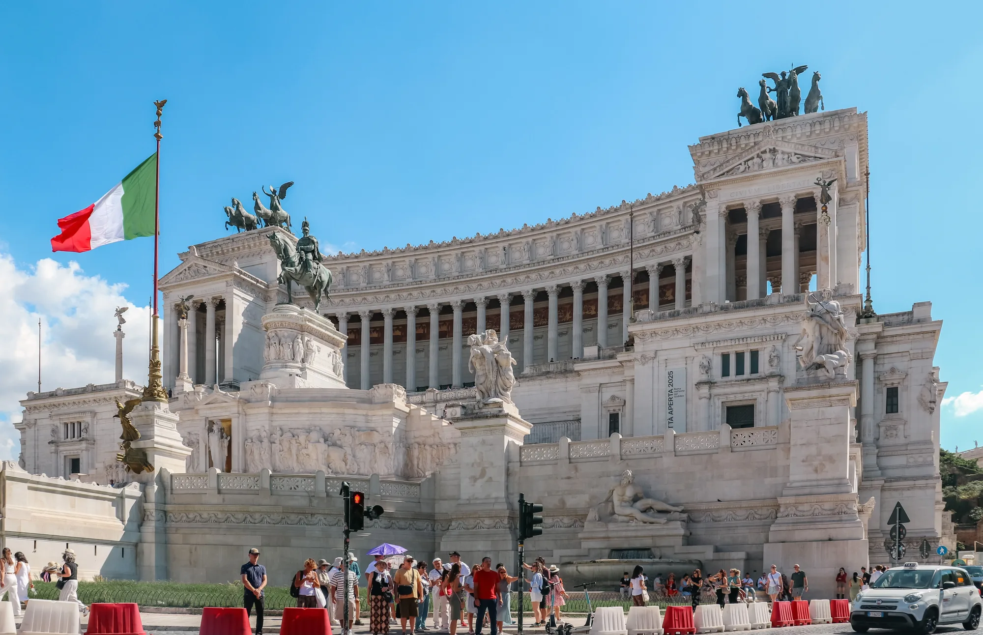 Besucher stehen vor dem Nationaldenkmal in Rom unter italienischer Flagge.