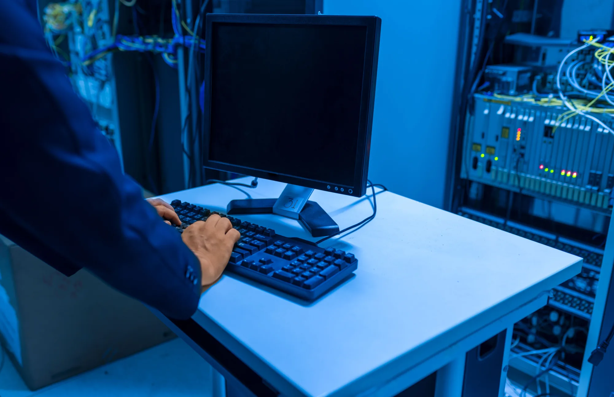 Eine IT-Fachkraft arbeitet an einem Rechner in einem Serverraum.