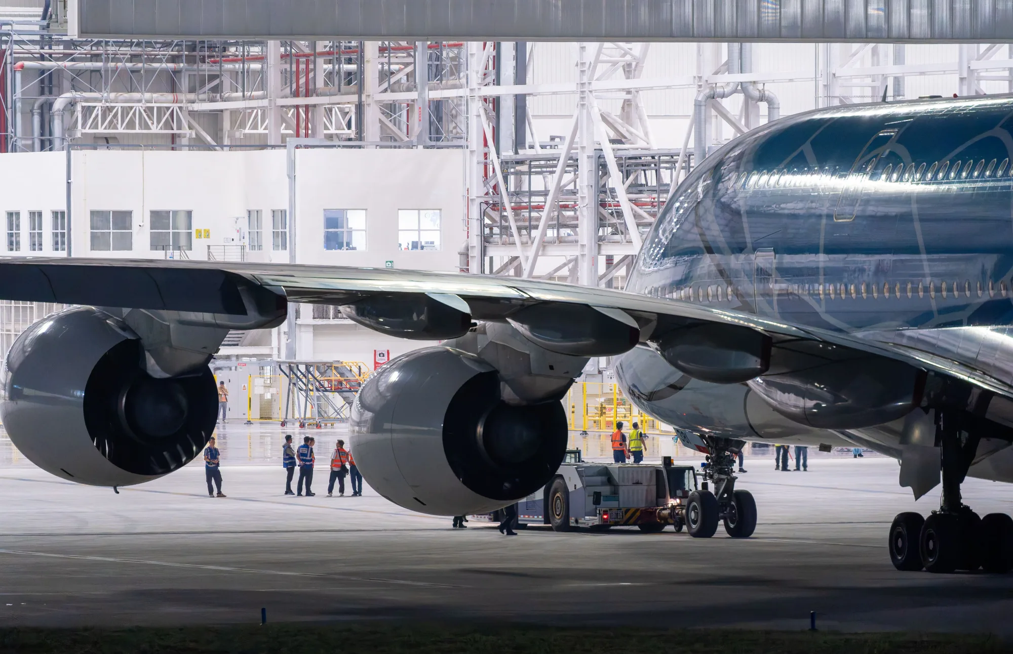 Ein Wartungsteam arbeitet an einem Verkehrsflugzeug in einer Hangarhalle.
