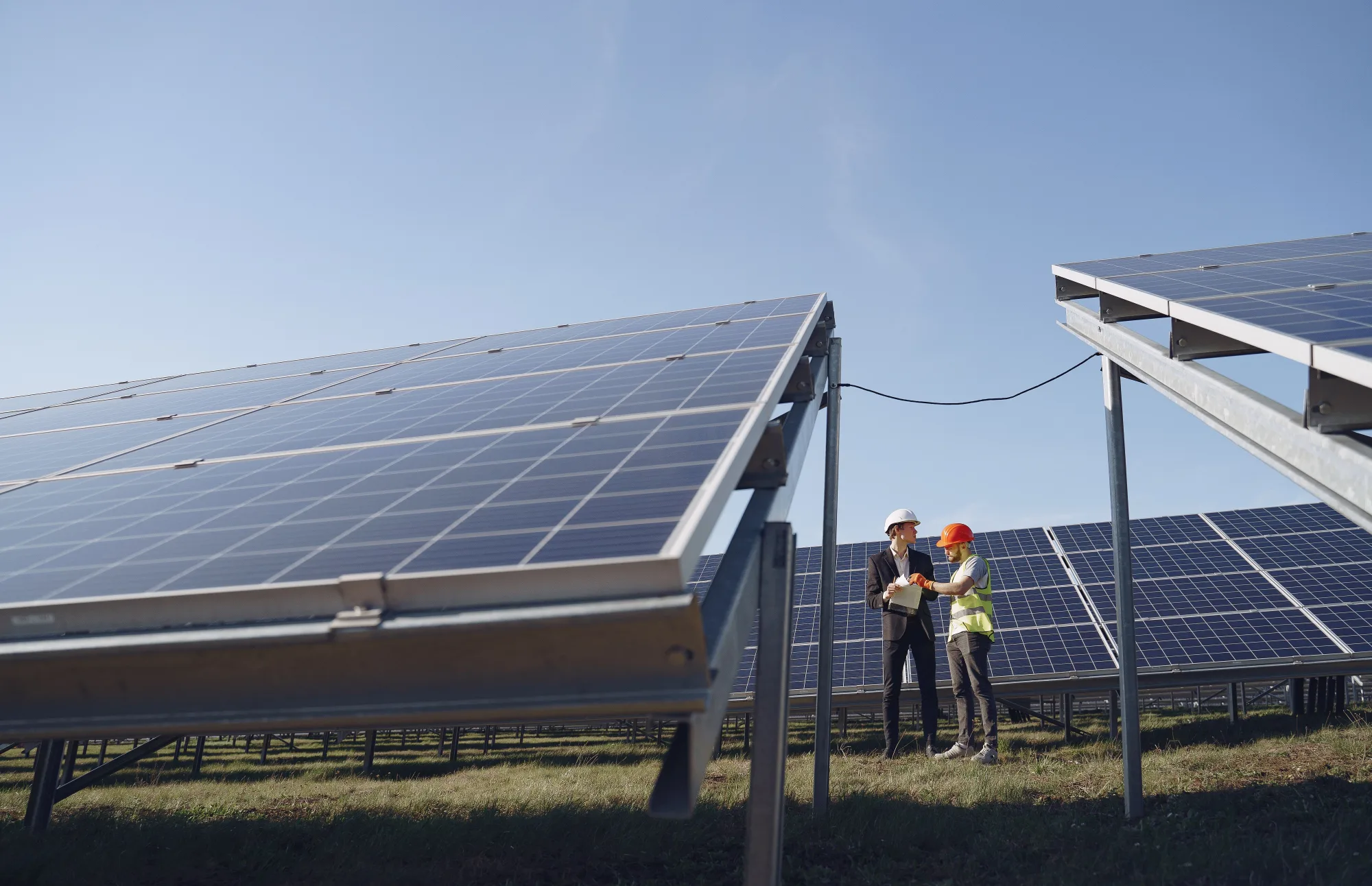 Zwei Fachleute besprechen Unterlagen an einer Solaranlage.