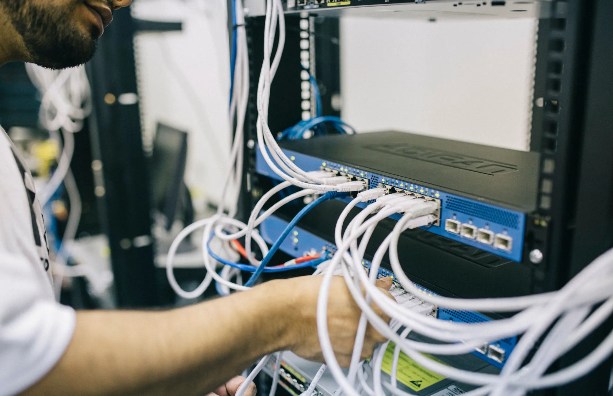 Ein IT-Techniker wartet Netzwerkhardware in einem Serverraum.