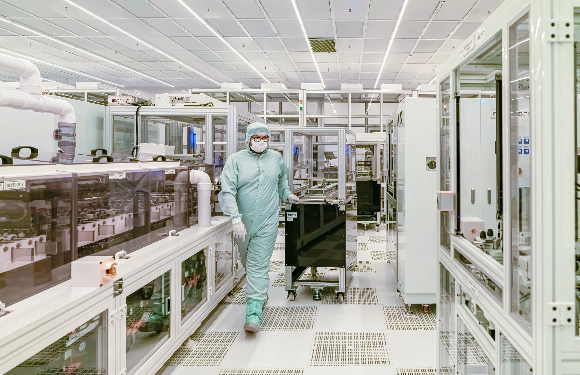 Eine Fachkraft arbeitet in einem hochreinen Produktionsbereich für Elektronik.