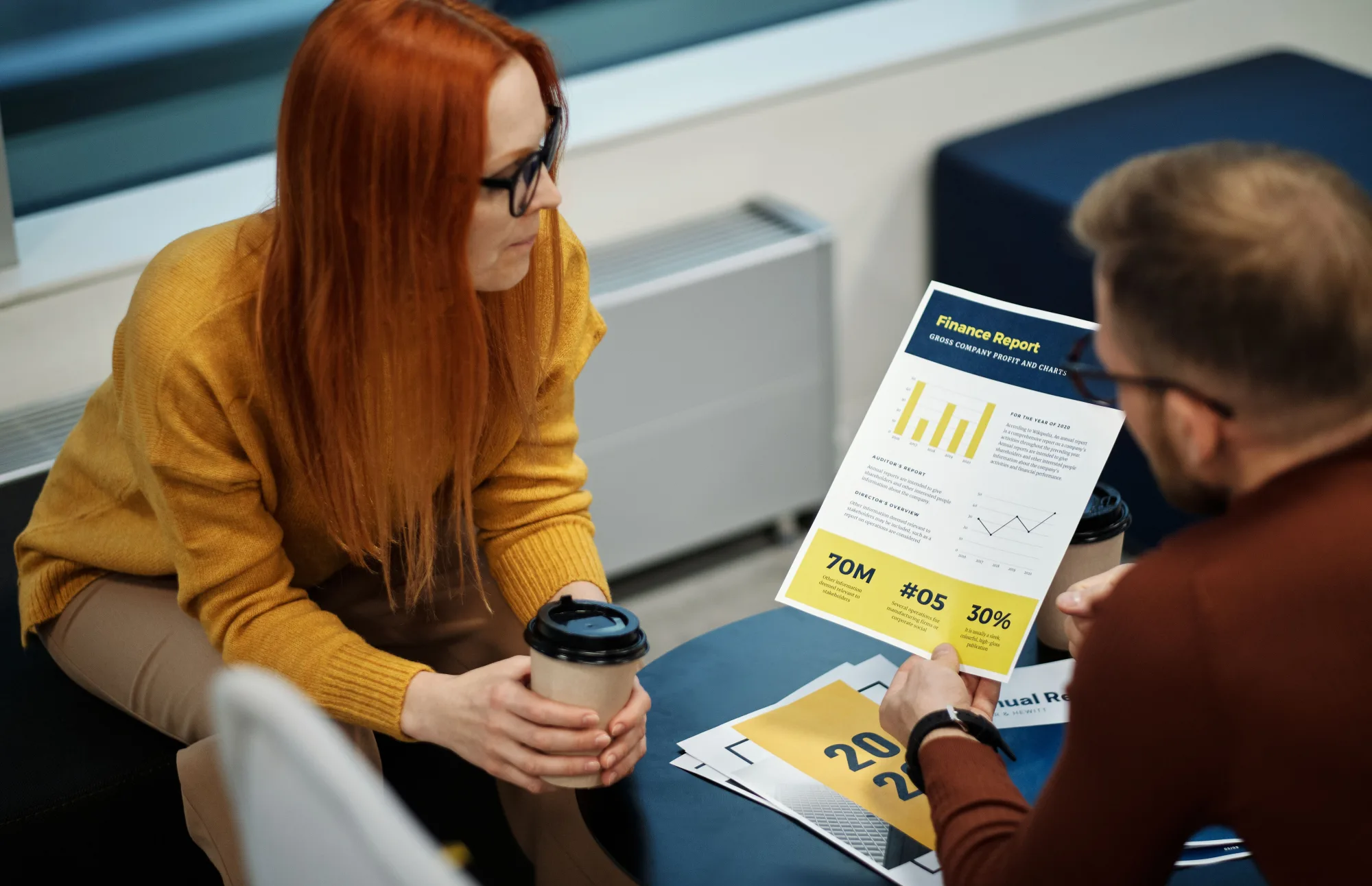 Zwei Kollegen vergleichen einen Finanzbericht in einem hellen Büro.