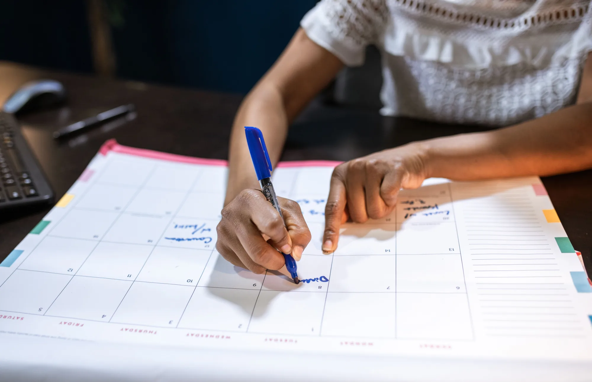 Eine Frau trägt wichtige Termine in einen großen Tischkalender ein.