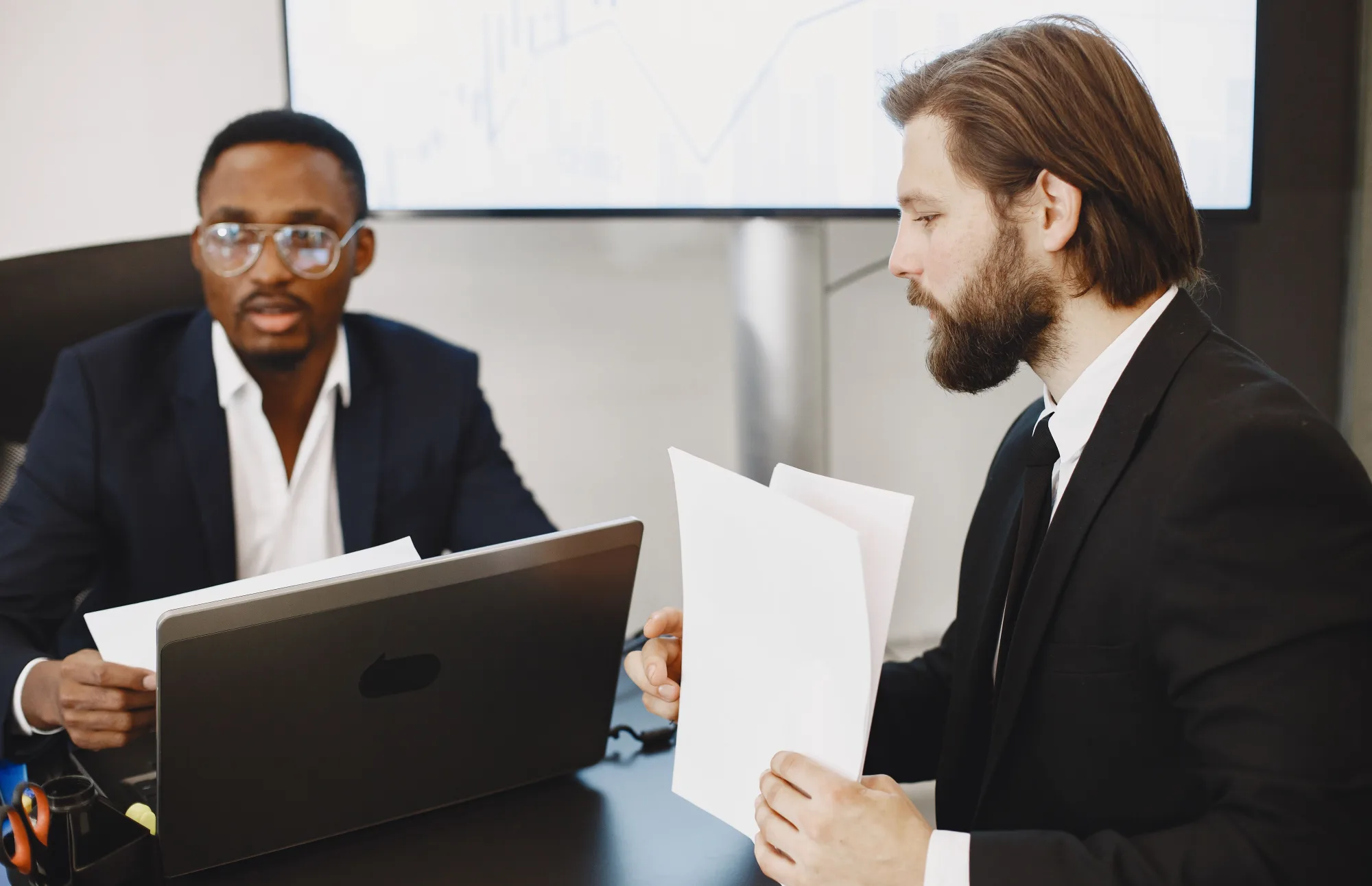 Zwei Finanzexperten beraten sich in einem hellen Büro.