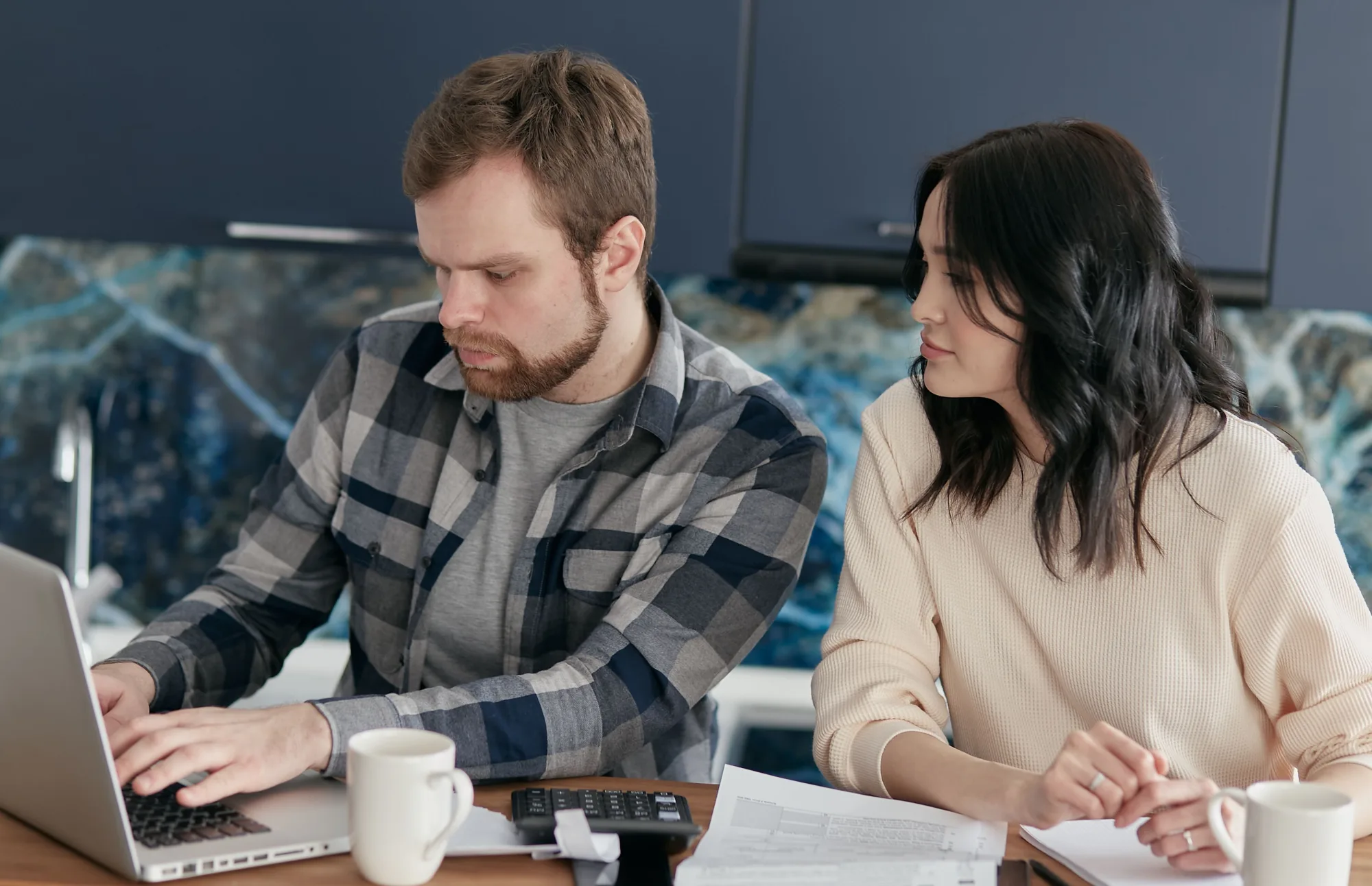 Ein Paar plant gemeinsam seine Finanzen mit Laptop und Unterlagen.