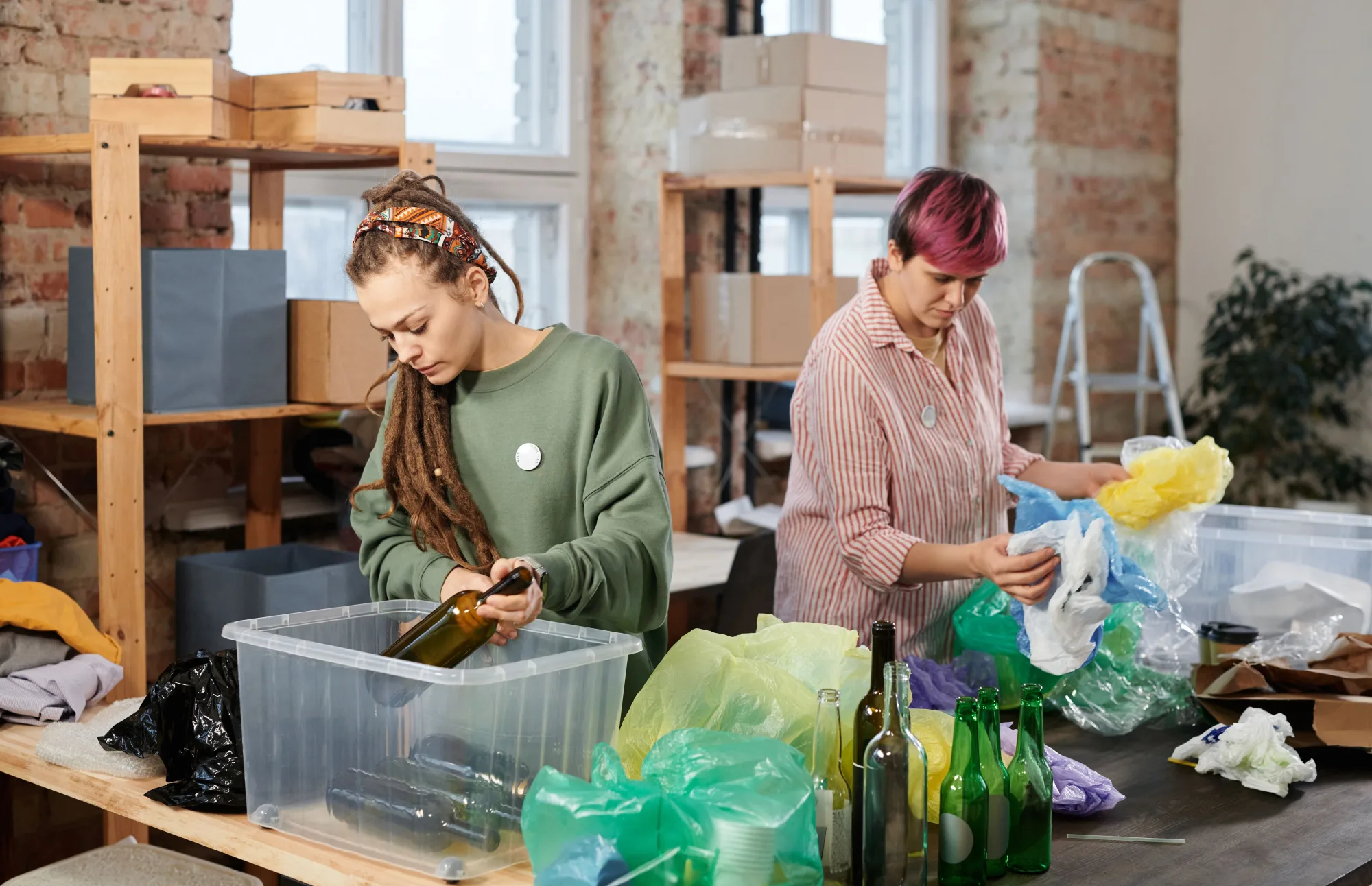 Zwei Frauen sortieren Glas und Kunststoff in einer Recyclingwerkstatt