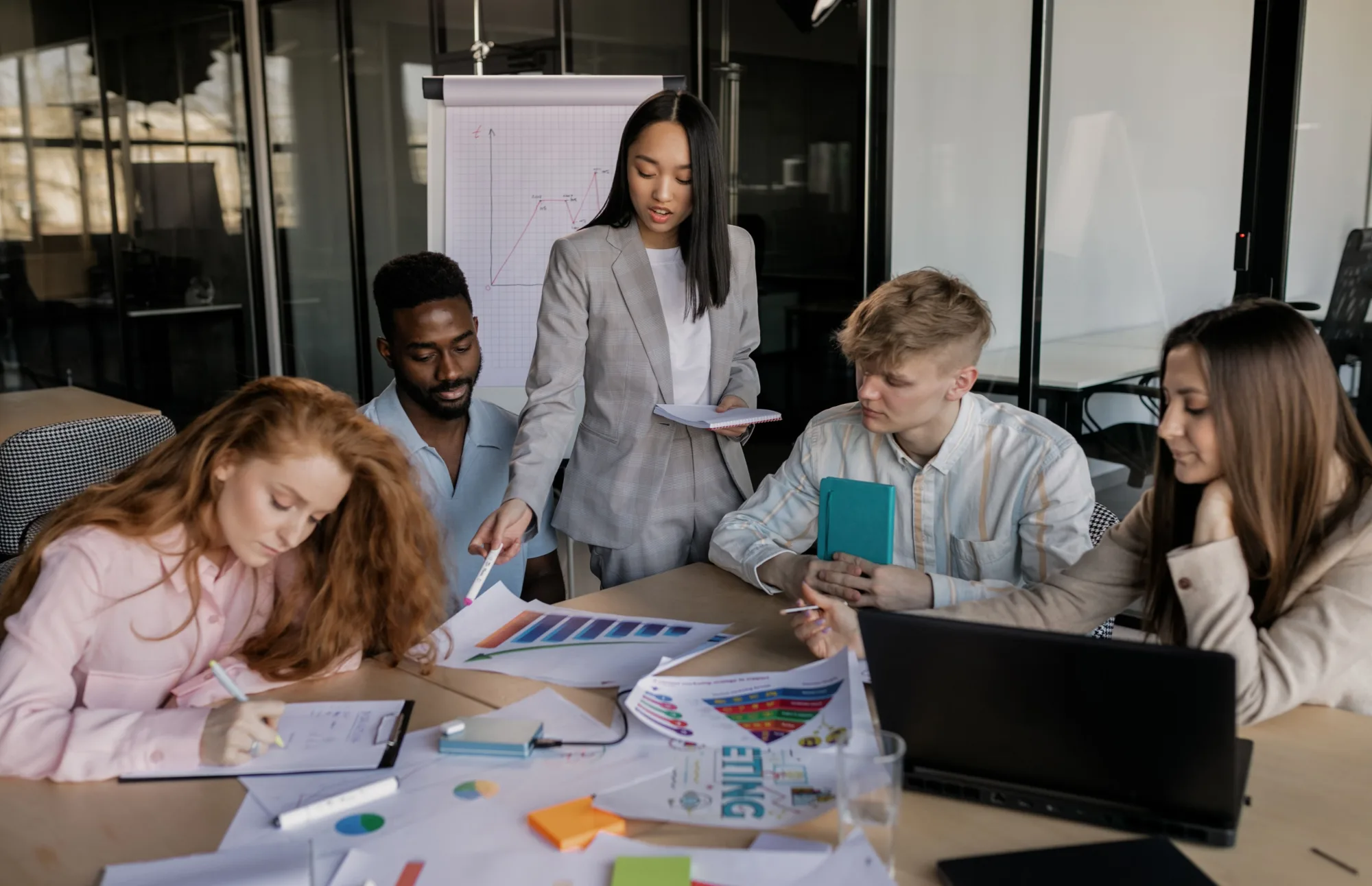 Ein diverses Team bespricht Geschäftskennzahlen in einem modernen Büro.