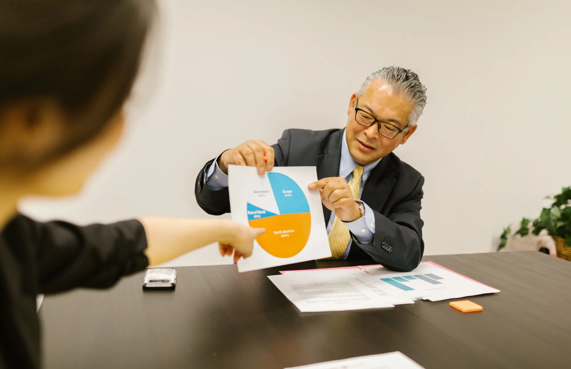 Japanischer Finanzberater erklärt Kunden ein farbiges Kreisdiagramm