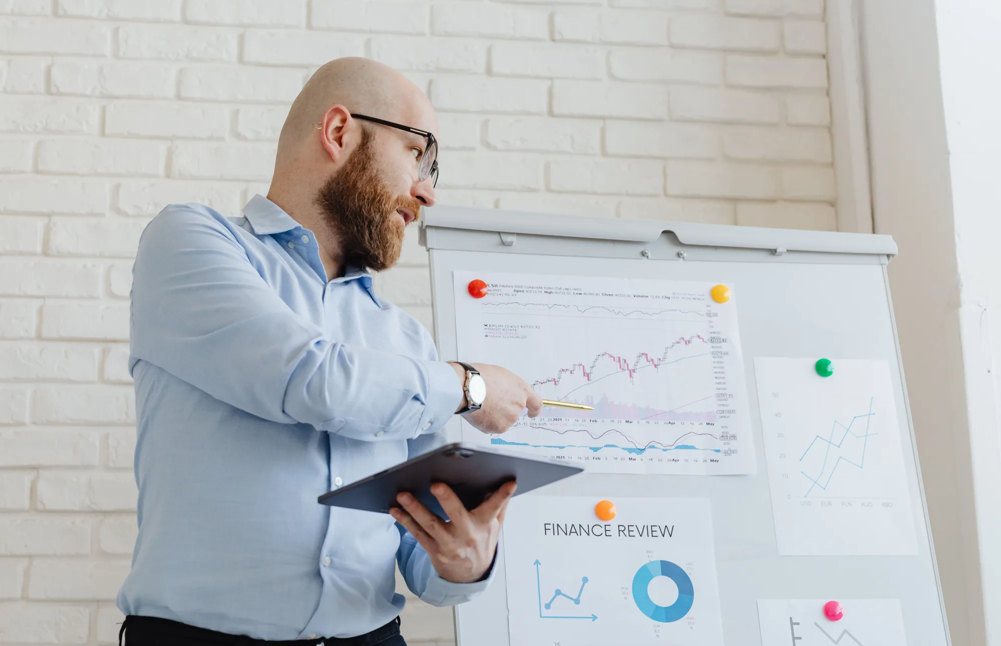 Portfoliomanager erläutert Finanzdiagramme mit einem Tablet am Whiteboard