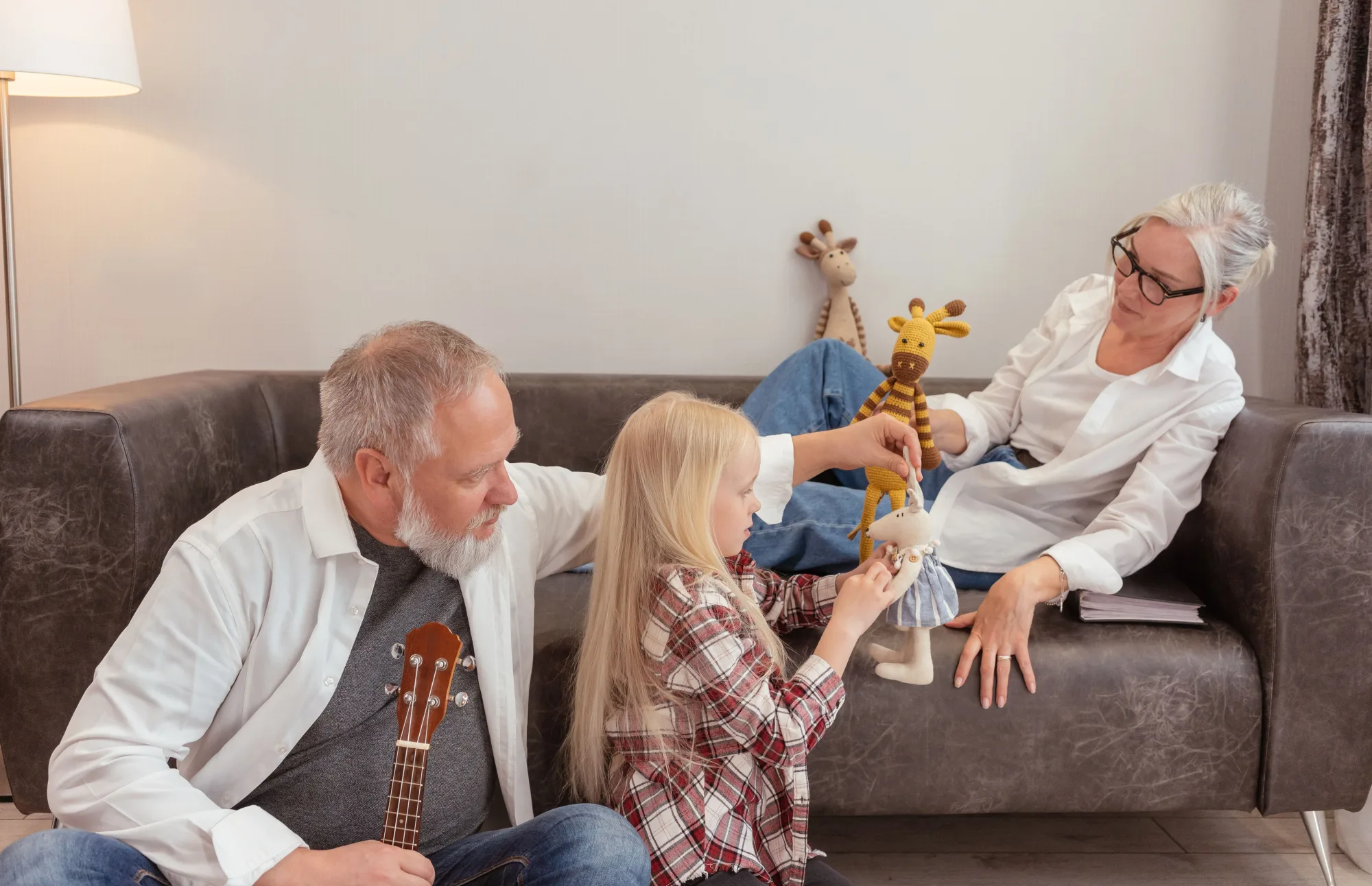 Großeltern spielen mit ihrer Enkelin im Wohnzimmer.