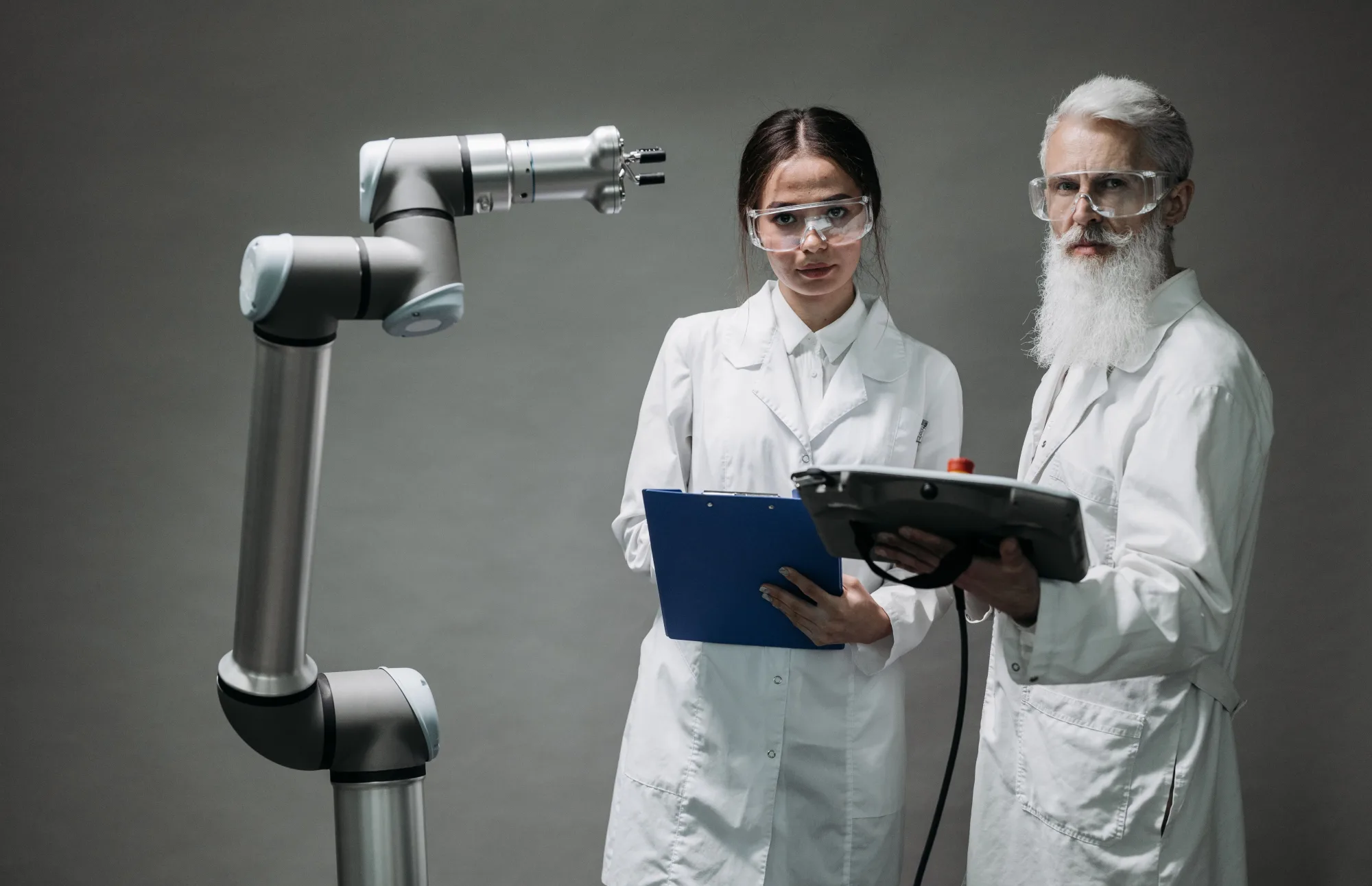 Zwei Forschende prüfen einen Roboterarm im Labor.