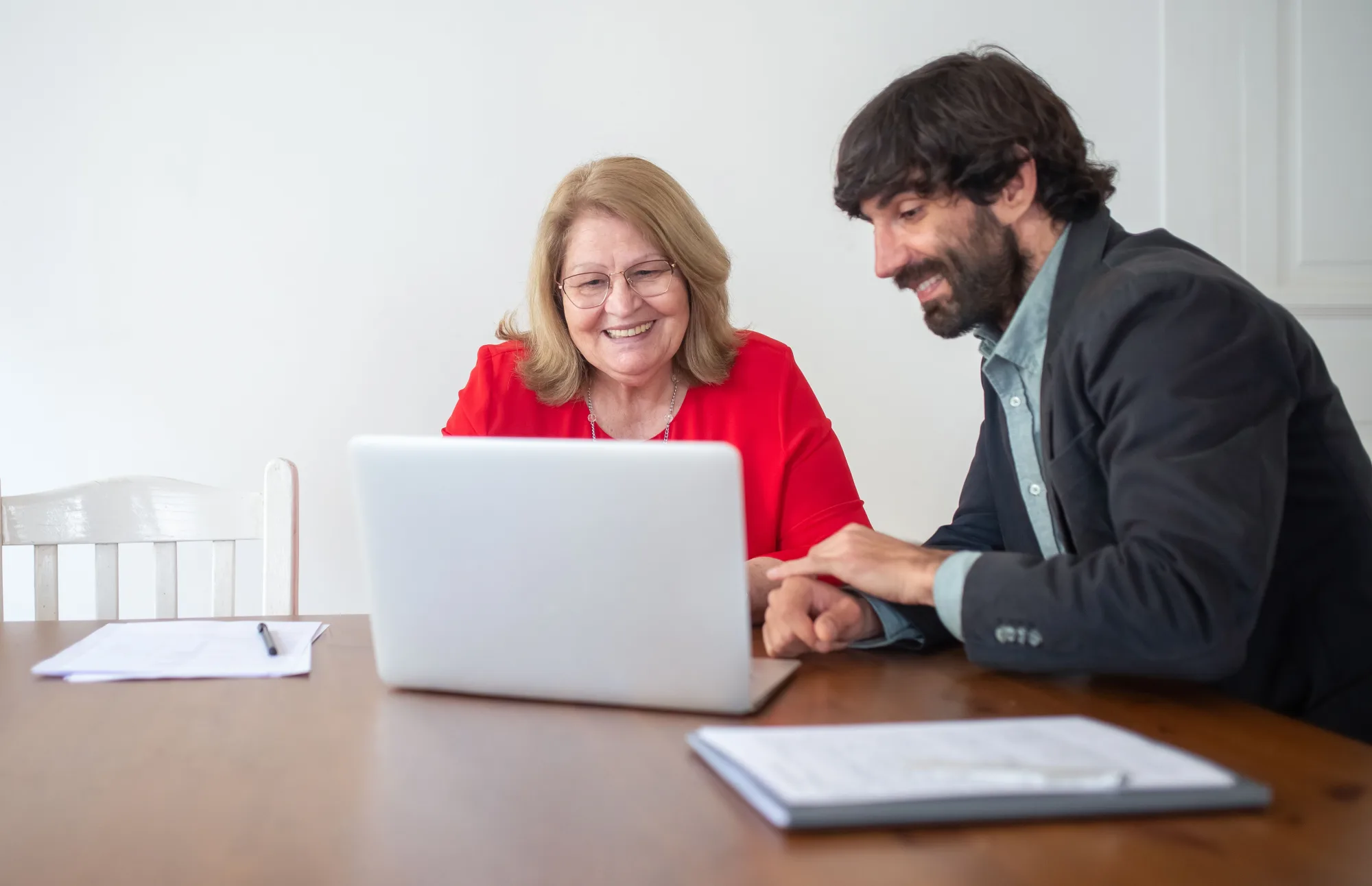 Eine ältere Frau arbeitet mit einem Kollegen an einem Laptop