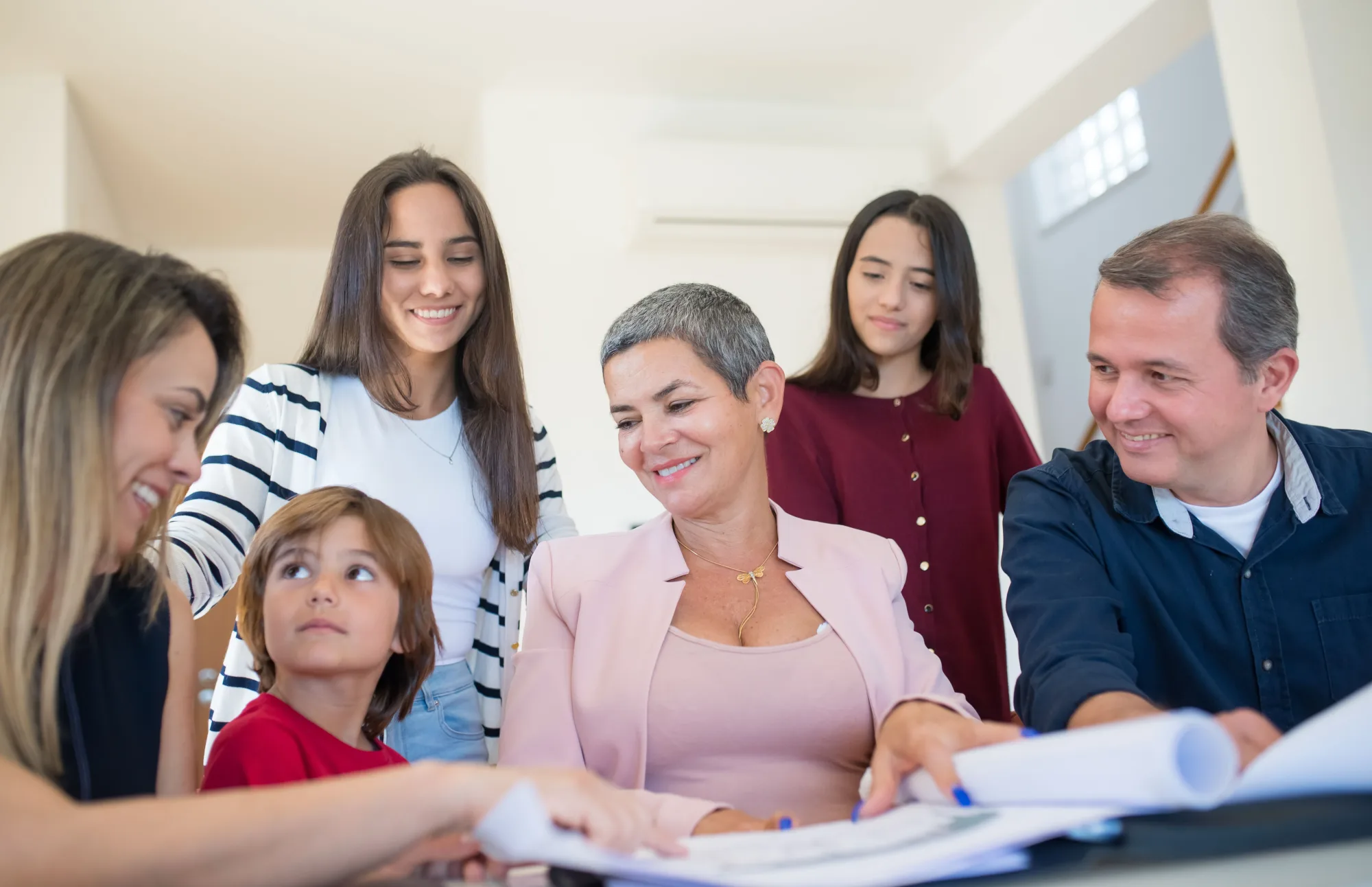 Eine Familie verschiedener Generationen bespricht Unterlagen mit einer Beraterin
