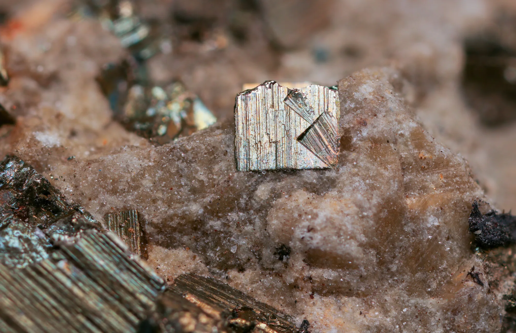 Metallisch glänzende Mineralkristalle in rauem Gestein
