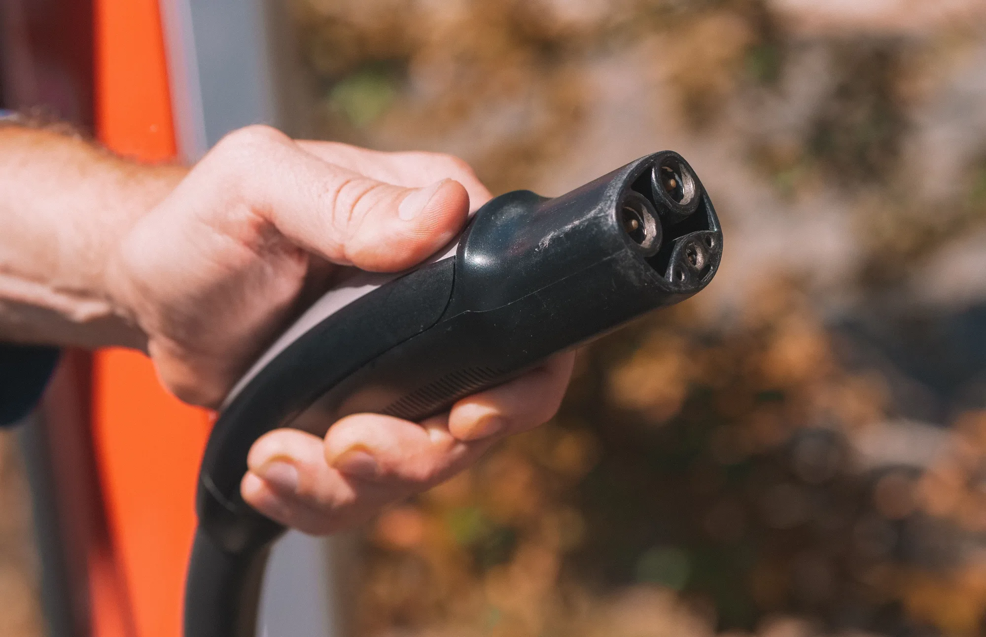 Eine Hand hält einen Ladestecker für ein Elektroauto