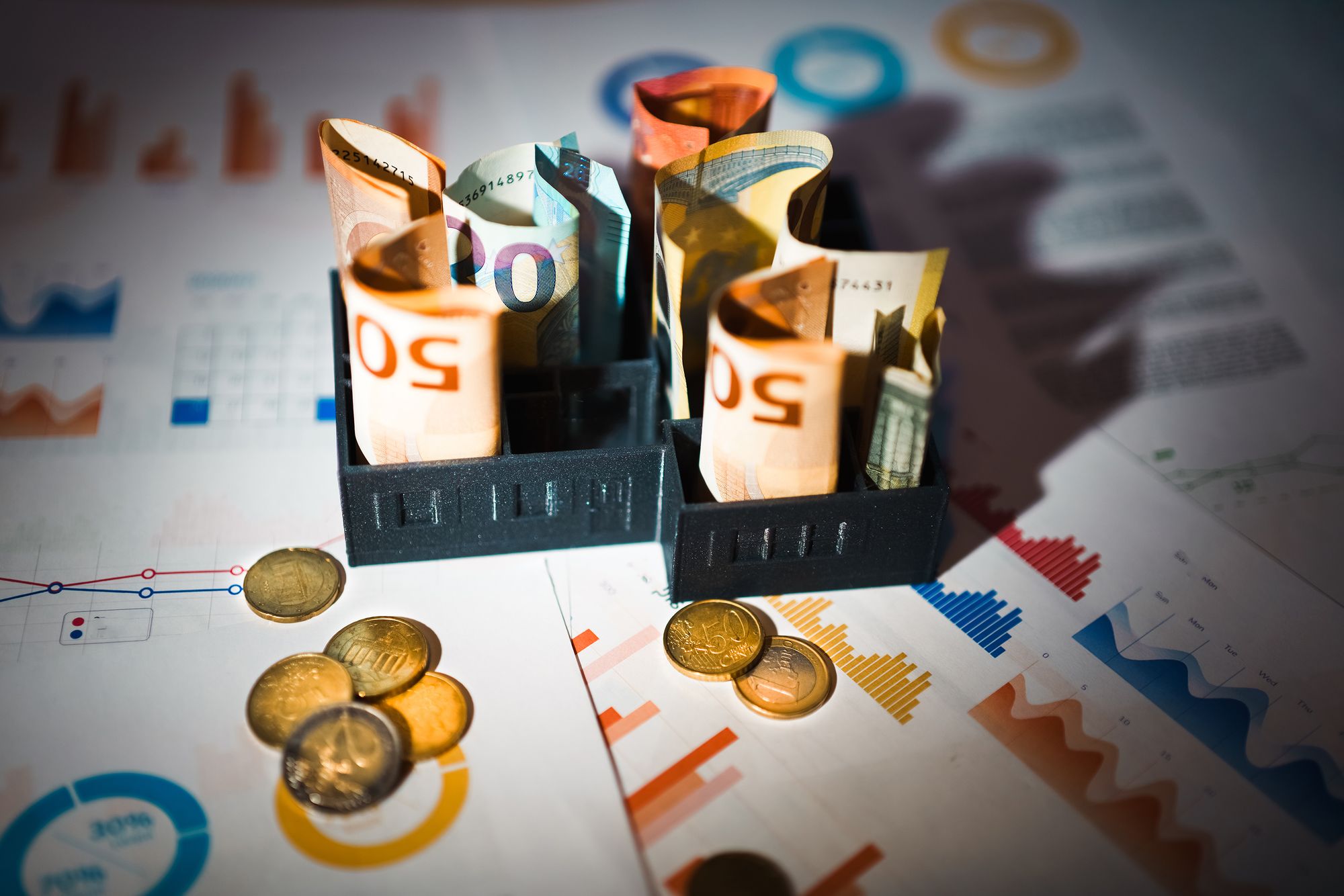 Euro-Scheine und Münzen auf Finanzcharts